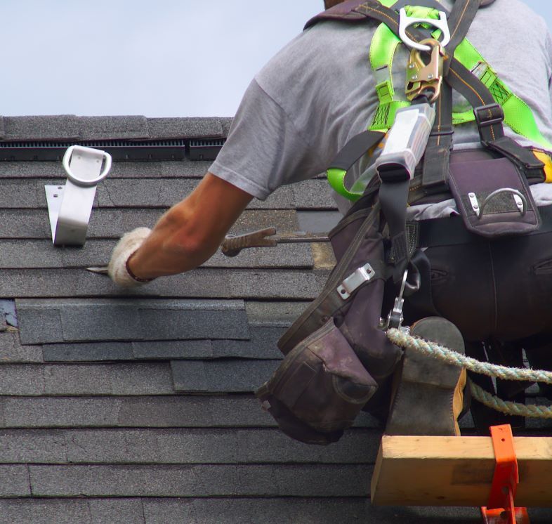 A roofer replacing shingles