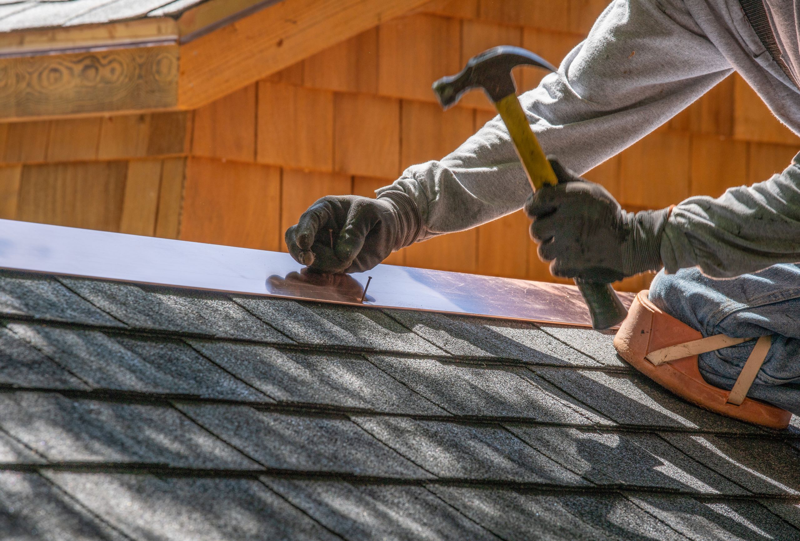 A person hammering a nail into a roof